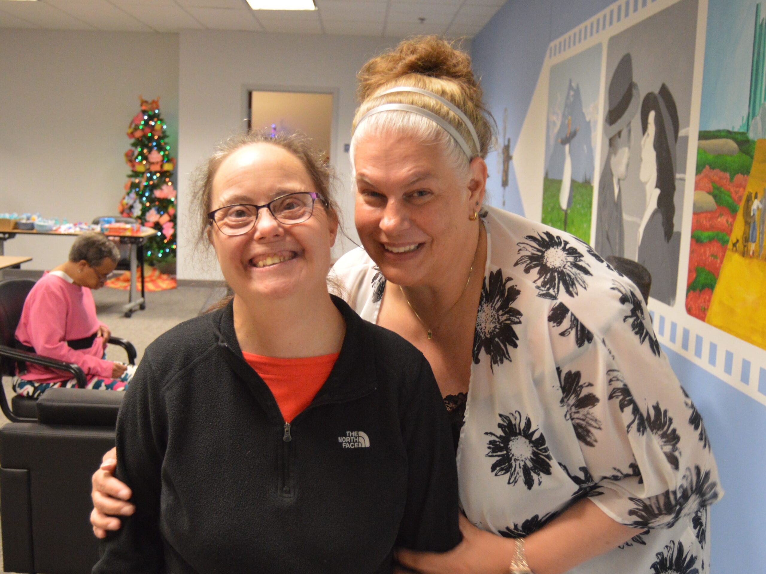 client and staff in memory care space in front of mural