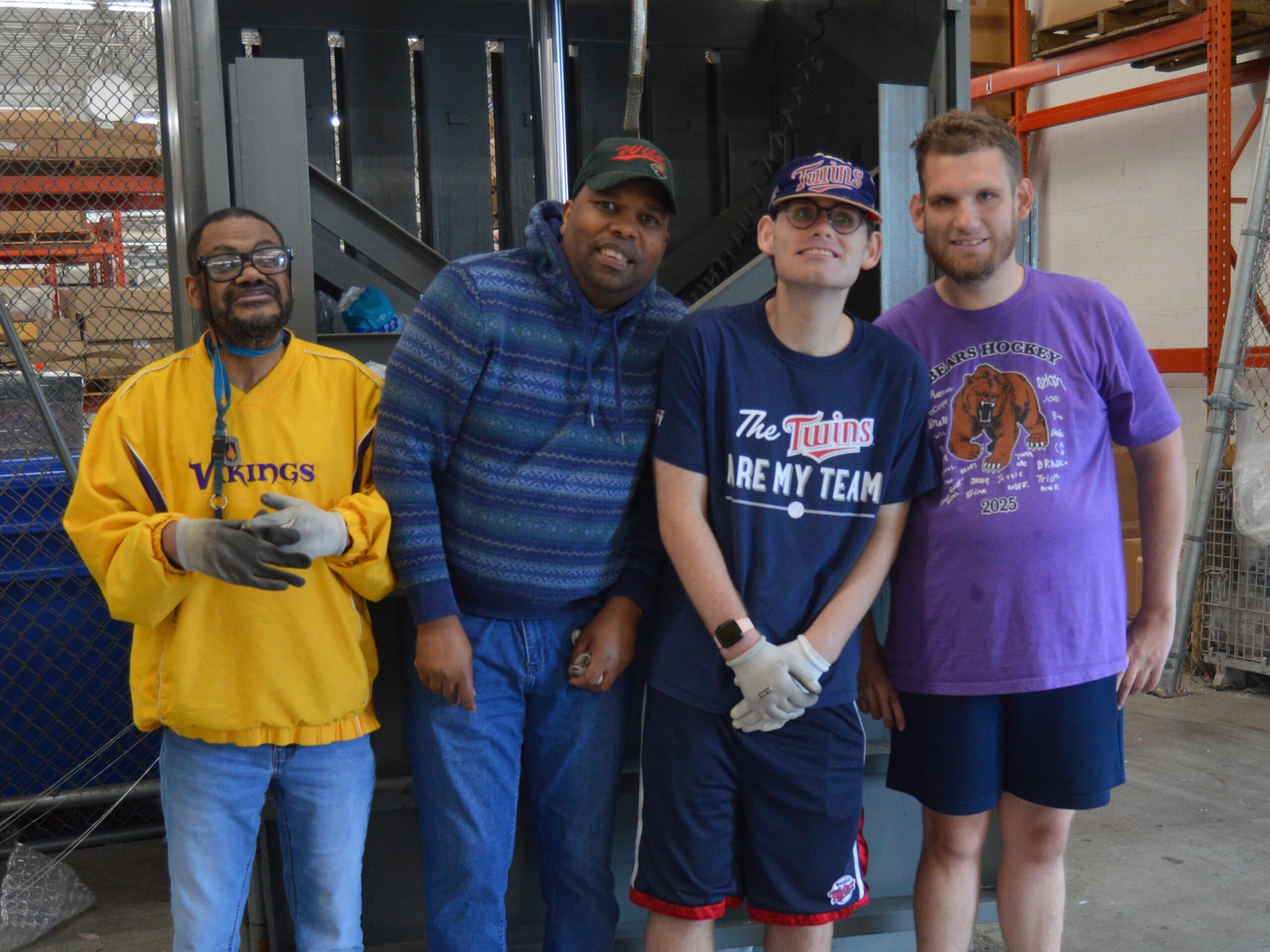 plastic recycling crew comprised of four clients in front of baler machine