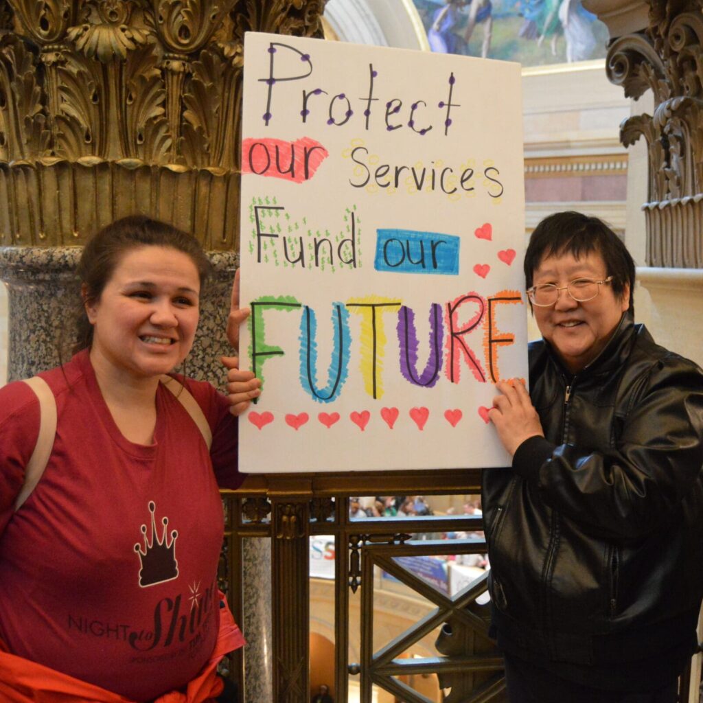 self-advocates at Disability Services Day at the State Capitol at the rally in the Rotunda holding up a sign