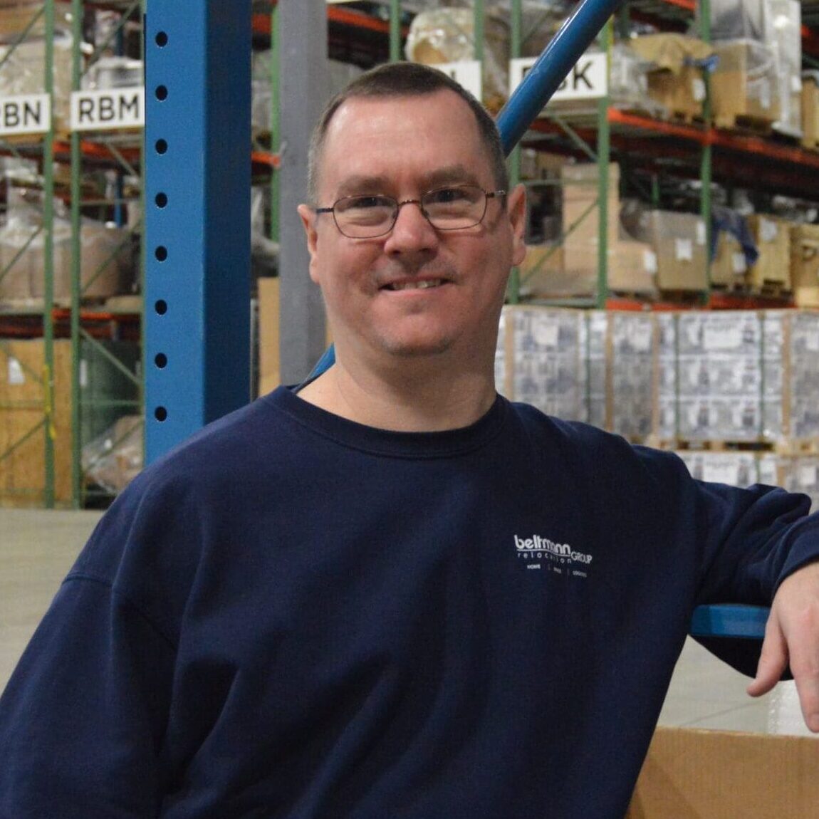 Individual employed at Beltmann Group stands in the warehouse workplace.