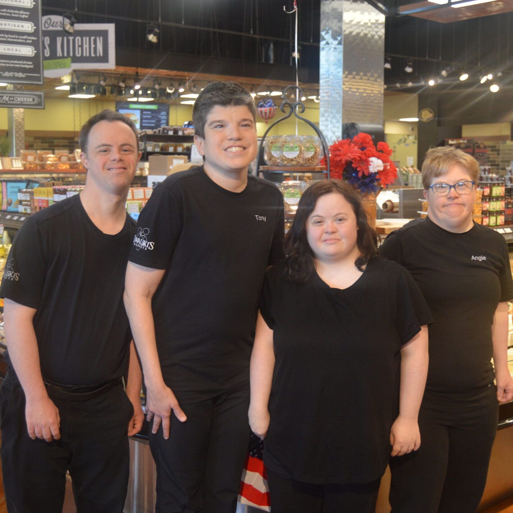 A work crew of four employees poses together in the deli department at Kowalski's Market.