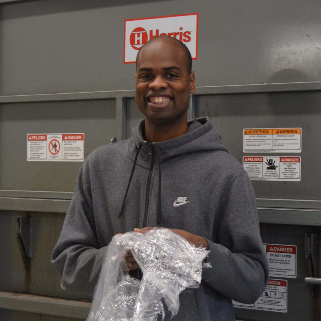 Lasean in front of baling machine with some plastic in hand
